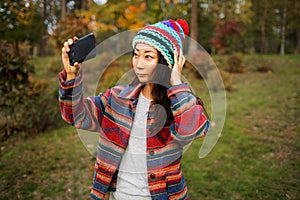 Cute Asian Teen Girl Taking Selfie In Autumn Forest. Candid Woman In Hat Enjoying Autumn In The Forest .