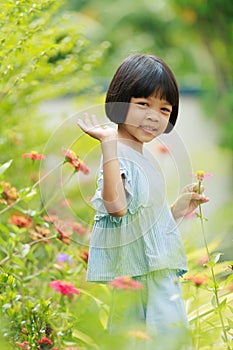 Cute Asian Thai kid girl with short hair, 4 to 6 years old, elementary school age. She is running around in the garden happily and