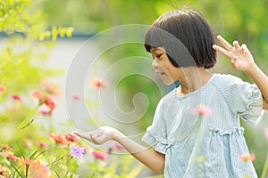 Cute Asian Thai kid girl with short hair, 4 to 6 years old, elementary school age. She is running around in the garden happily and