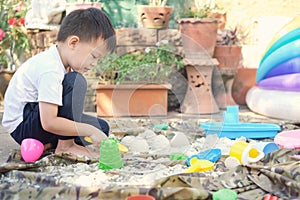 Cute Asian toddler boy playing with sand alone at home, Kid playing with sand toys in urban home garden , Montessori education,