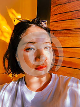 Cute Asian woman with bright make-up with sun dogs on face against yellow wall. Pretty Korean girl selfie picture. Soft