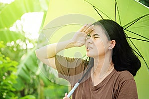 Cute asian woman holding umbrella with sunlight in the hot weather