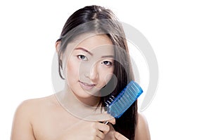 Cute Asian woman with long hair brushing hair