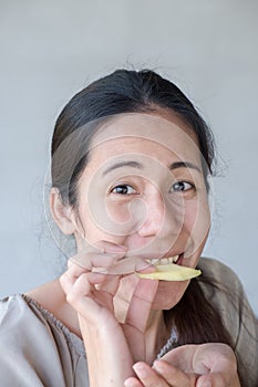 Cute asian woman tasting sour lemon.