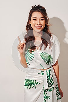 Cute asian woman in tropical print green dress thinking and imagination on white background