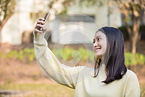 Cute Asian women are using their phones to take selfies and smile happy in the garden at home