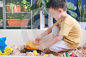 Cute Asian young boy playing with sand alone Kid playing with sand toys in urban home garden , Montessori education, Creative play