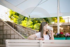 Cute asian young woman in summer cafe outdoors. girl In white T-shirt, with long hair in simple light cozy interior of restaurant