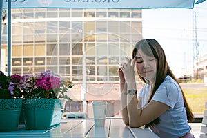 Cute asian young woman in summer cafe outdoors. girl In white T-shirt, with long hair in simple light cozy interior of restaurant