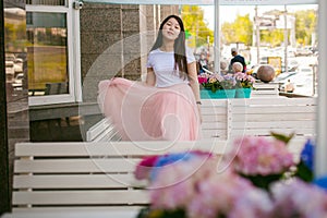 Cute asian young woman in summer cafe outdoors. girl In white T-shirt, with long hair in simple light cozy interior of restaurant