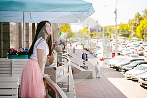 Cute asian young woman in summer cafe outdoors. girl In white T-shirt, with long hair in simple light cozy interior of restaurant