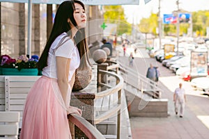 Cute asian young woman in summer cafe outdoors. girl In white T-shirt, with long hair in simple light cozy interior of restaurant