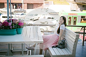 Cute asian young woman in summer cafe outdoors. girl In white T-shirt, with long hair in simple light cozy interior of restaurant