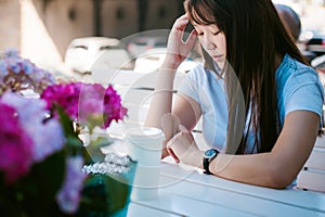 Cute asian young woman in summer cafe outdoors. girl In white T-shirt, with long hair in simple light cozy interior of restaurant