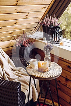 Cute autumn home decor arrangement. Tiny wooden cabin balcony with heather flowers in pot.