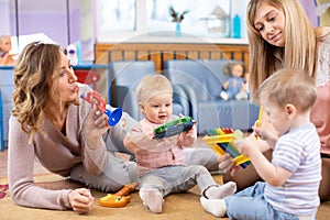 Cute babies playing musical toys with teacher and assistant. Early musical education in kindergarten