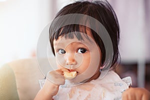 Cute baby asian child girl eating healthy food by herself