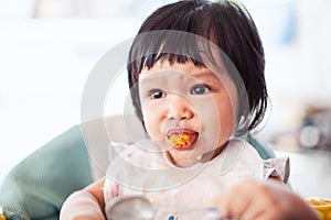 Cute baby asian child girl eating healthy food by herself