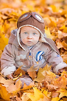 Cute baby in autumn leaves.