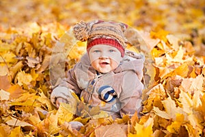 Cute baby in autumn leaves.