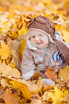 Cute baby in autumn leaves.