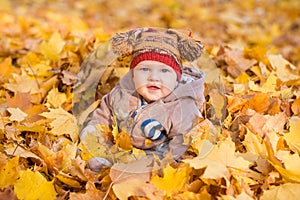 Cute baby in autumn leaves.