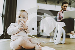 Cute Baby Bites Iron Cord while Mother Networking