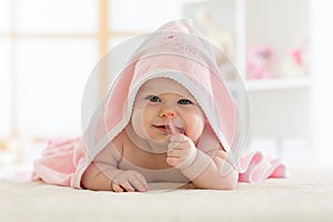 Cute baby biting teether under a hooded towel after bath