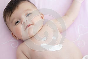 Cute baby with body cream on tummy