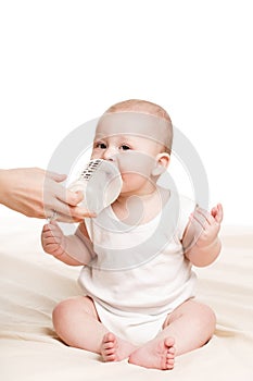 Cute baby with a bottle of milk on a beige blanket