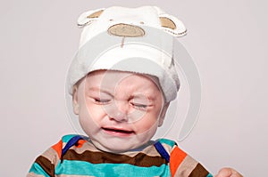 Cute baby boy with adorable hat crying.