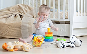 Cute baby boy assembling toy tower on floor. Concept of baby education