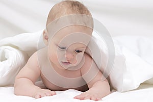 Cute baby boy in bed under a fluffy blanket