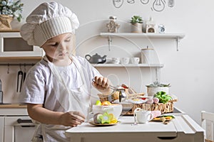 Cute baby boy chef uniform cooking playthings vegetable salad at childish kitchen enjoy childhood