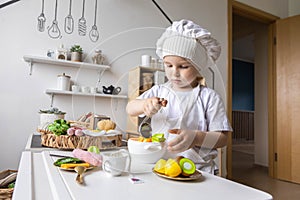 Cute baby boy chef uniform cooking playthings vegetable salad at childish kitchen enjoy childhood