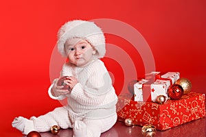 Cute baby boy with christmas decorations over red
