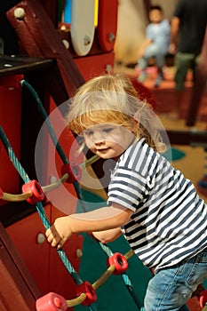 Cute baby boy climbing rope net or ladder