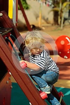 Cute baby boy climbing rope net or ladder