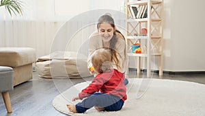 Cute baby boy crawling on floor to his mother and throwing a ball. Baby development, family playing games, making first steps,