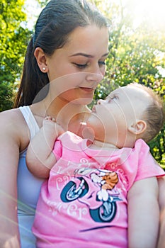 Cute baby boy with Down syndrome and his young mother in summer day