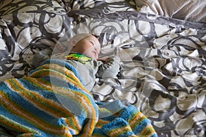Cute baby boy with Down syndrome sleeping on the bed