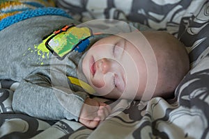 Cute baby boy with Down syndrome sleeping on the bed