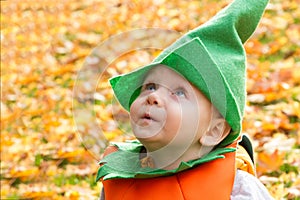 A Cute Baby Boy Dress As A Pumpkin Surrounded By Autumn Leaves