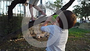 Cute baby boy drinking water and looking dady climbing on the tree