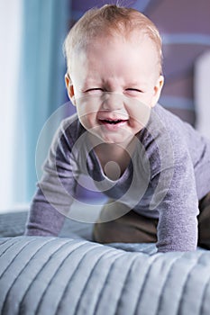 Cute baby boy with funny face expression looing at camera. An infant kid makes a face. Squinting boy