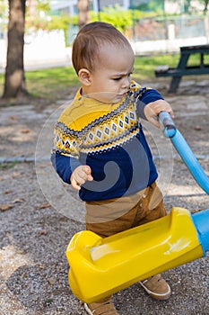 Cute baby boy having fun on outdoor playground. Toddler activities. Serious baby swinging on swing