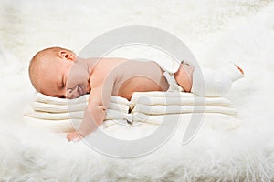 Cute baby boy lying on stack of towels