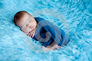 Cute baby boy, peacefully sleeping wrapped in blue wrap