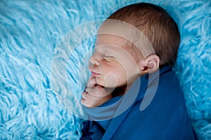 Cute baby boy, peacefully sleeping wrapped in blue wrap