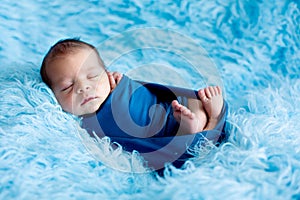 Cute baby boy, peacefully sleeping wrapped in blue wrap